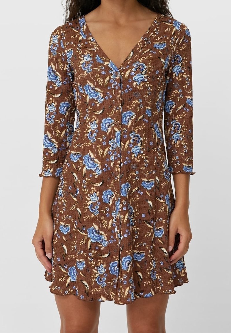 Robe marron longueur genou avec un motif floral en bleu et crème. Présente un col en V et des manches trois-quarts, confectionnée dans un tissu texturé.