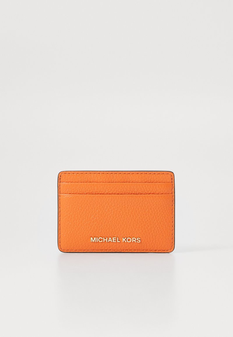 Oranžinės odinės kortelių laikiklis su tekstūriniu paviršiumi, turintis keturis skyrius ir įspaustą „MICHAEL KORS“ logotipą metalizuotu raštu apačioje.