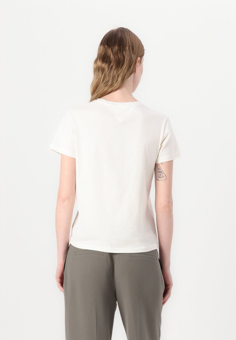 T-shirt en coton crème à manches courtes, à encolure ronde et avec un ourlet légèrement plongeant. Présente un petit détail de couture au dos.