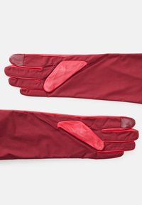 Red gloves made of smooth fabric with leather accents. Features include finger coverings and padded zones for grip.