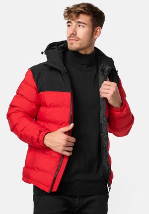 Veste rembourrée rouge et noire avec un col haut, une fermeture éclair et des poignets élastiques. Le design comprend un motif en blocs de couleurs.