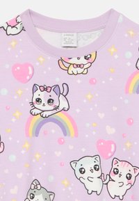 Lila Stoff mit Cartoon-Katzen, Regenbögen, Herzen und Sternen in lebhaften Farben. Rundhalsausschnitt, weicher Stoff, verspieltes Muster.