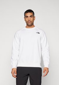 Witte sweatshirt van zacht materiaal met een ronde halslijn en geribde manchetten. Heeft een klein zwart logo op de linkerkant van de borst.