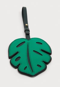 Grøn lædermærke formet som et monstera-blad med udskårne detaljer og sorte kanter. Har en grøn rem med guldhardware.