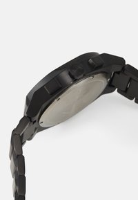 Orologio analogico nero con cassa e cinturino in acciaio inox, corona esagonale e design minimalista con quadrante liscio e solido.