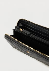 Czarny pikowany skórzany portfel z zapięciem na złoty zamek błyskawiczny, licznymi miejscami na karty oraz zamykaną przegródką na monety lub drobne przedmioty.