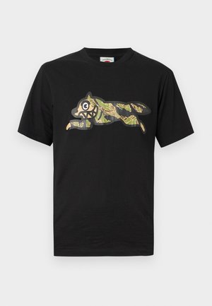 Black cotton t-shirt featuring a green and tan camo graphic of a leaping animal with bold outlines and exaggerated facial features.