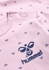 Lyserød bomuldsbluse med marineblåt bi-mønster og logo. Har trykknapper ved kraven og en blød, glat tekstur.