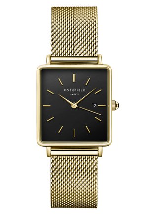 Montre à cadran noir carré avec un bracelet en maille dorée, comprenant des index d'heure minimalistes, un affichage de la date et une couronne sur le côté droit.