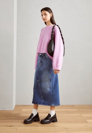 Maglione lavorato a maglia rosa, gonna midi in denim blu con cucitura diagonale, mocassini neri con tacco chunk e borsa a tracolla nera.