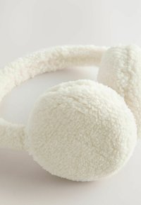 Fuzzy white earmuffs with circular, plush ear covers and a soft fabric headband, designed for warmth and comfort.