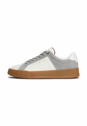 Zapatilla blanca y gris con materiales de ante y cuero, suela de goma, puntera redonda, cordones planos y detalle del logo en el costado.