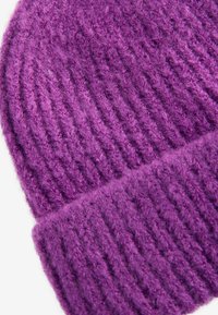 Bonnet en tricot violet avec une texture côtelée. Fabriqué à partir d'un matériau doux et poilu, il possède un revers replié en bas.