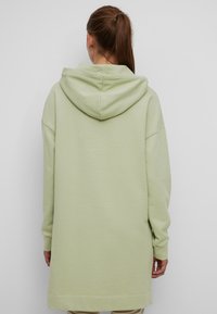 Felpa con cappuccio verde chiaro, dal taglio morbido e rilassato, maniche lunghe e orlo dritto. Tessuto morbido con un motivo sottile.