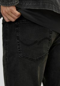 Svarta denimjeans med slim fit. Har en kurvad sömdesign på bakfickan, synlig textur och subtila blekningar.