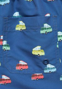 Modrý textil s kapsou, na které je vzor malých barevných obytných automobilů v červené, žluté, zelené a modré barvě, s kontrastním stehem.