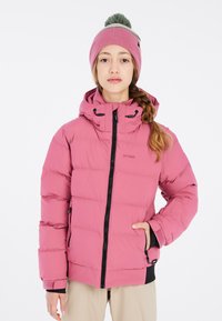 Giacca isolante rosa con chiusura zip, cappuccio e polsini elasticizzati. Presenta un design imbottito e due tasche laterali. Indossata con un berretto rosa coordinato.