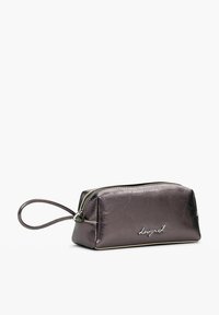 Pochette cosmetica di colore viola metallico con chiusura a zip, forma arrotondata e un cinturino da polso. Presenta il nome del marchio in rilievo di colore argento.