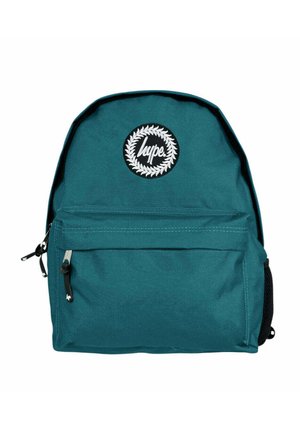 Teal kangaskassi pyöreällä muodolla, etupuolella vetoketjullinen tasku ja ympyrän muotoinen valkoinen logo, jossa lukee "hype" laakeriseppeleet ympäröimänä.