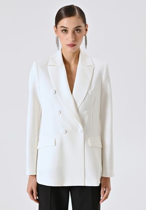 White double-breasted blazer with a notched collar, two front pockets, and smooth texture, paired with black trousers.