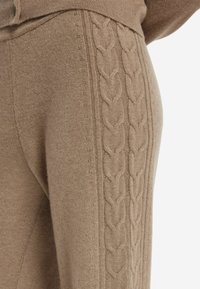Brązowy sweter dziergany z fakturowanym wzorem w warkocz po bokach. Miękki materiał o gładkim wykończeniu i subtelnych detalach.