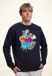 Granatowy sweatshirt z okrągłym dekoltem, zdobiony kolorową grafiką z elementami kreskówkowymi oraz tekstem w stylu graffiti z przodu.