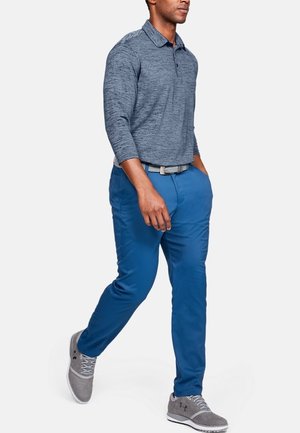 Pánské polo s dlouhým rukávem v barvě heather navy, spojeno s jasně modrými kalhotami. Šedé boty mají tonální akcenty a šněrování.