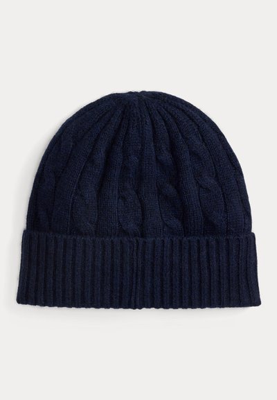 Tumši zila adīta cepure ar kabelīšu rakstu, ribotu maliņu un mīkstu tekstūru, kas izstrādāta, lai nodrošinātu siltumu un komfortu.