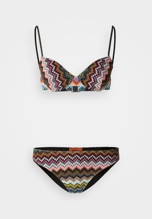 Bikinisetti, jossa on siksak-kuvio eri väreissä, kuten musta, pinkki ja sininen, säädettävillä olkaimilla ja teksturoidulla kankaalla.