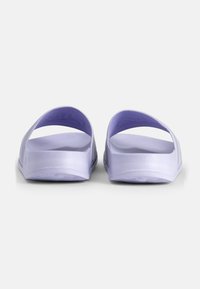 Lila slidesandaler med öppen tådesign och slät plasttextur. Har en lätt båge i sulan och ingen synlig hårdvara.