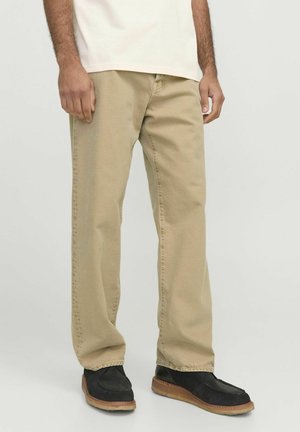 Beige, loose-fitting pants with a straight leg design. Fabric has a slight texture, featuring seam details and stitched hems. Paired with black shoes.