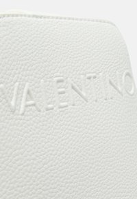 Prodotto in pelle bianca texturizzata con il marchio "Valentino" impresso. Superficie liscia con una sottile trama e bordi puliti.