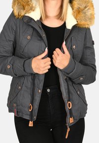 Szara kurtka z kapturem z sztucznego futra, zamkiem błyskawicznym i zapięciem na napy, ściągaczami przy mankietach oraz beżowymi akcentami. Posiada wiele kieszeni oraz pikowany krój.