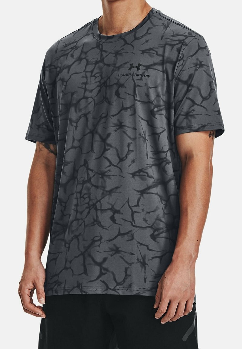 Grå sportt-shirt med ett svart abstrakt mönster, korta ärmar, rund hals och Under Armour-logotyp. Tillverkad av ett slätt, lätt material.