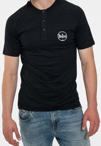 Black short-sleeve henley t-shirt with a crew neckline, three-button placket, and white "The Beatles" logo printed on the chest.