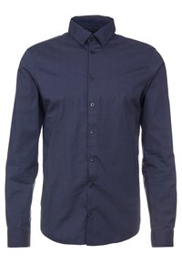 Långärmad skjorta i mörk marinblått tyg, med ett geometriskt mönster av vita prickar, klassisk krage och framknäppning med matchande knappar.
