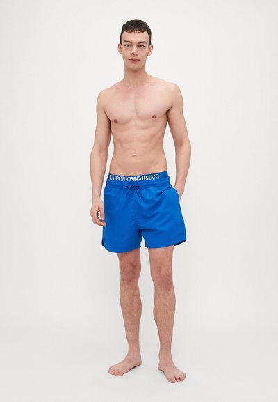 Shorts de bain bleu électrique avec une taille élastique ornée de la marque "EMPORIO ARMANI", coupe droite et texture lisse.