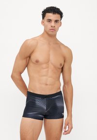 Schwarze Badehose mit geometrischem Muster in Grautönen, ausgestattet mit einem Kordelzugbund und einer körpernahen Passform.