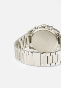 Silver stainless steel watch with a linked band, round case back, and visible chronograph pushers. Polished finish.