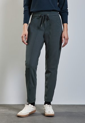 Pantalons joggers vert foncé en matériau léger et extensible. Dotés d'une taille avec cordon de serrage, d'une coupe fuselée et de détails en panneaux latéraux.