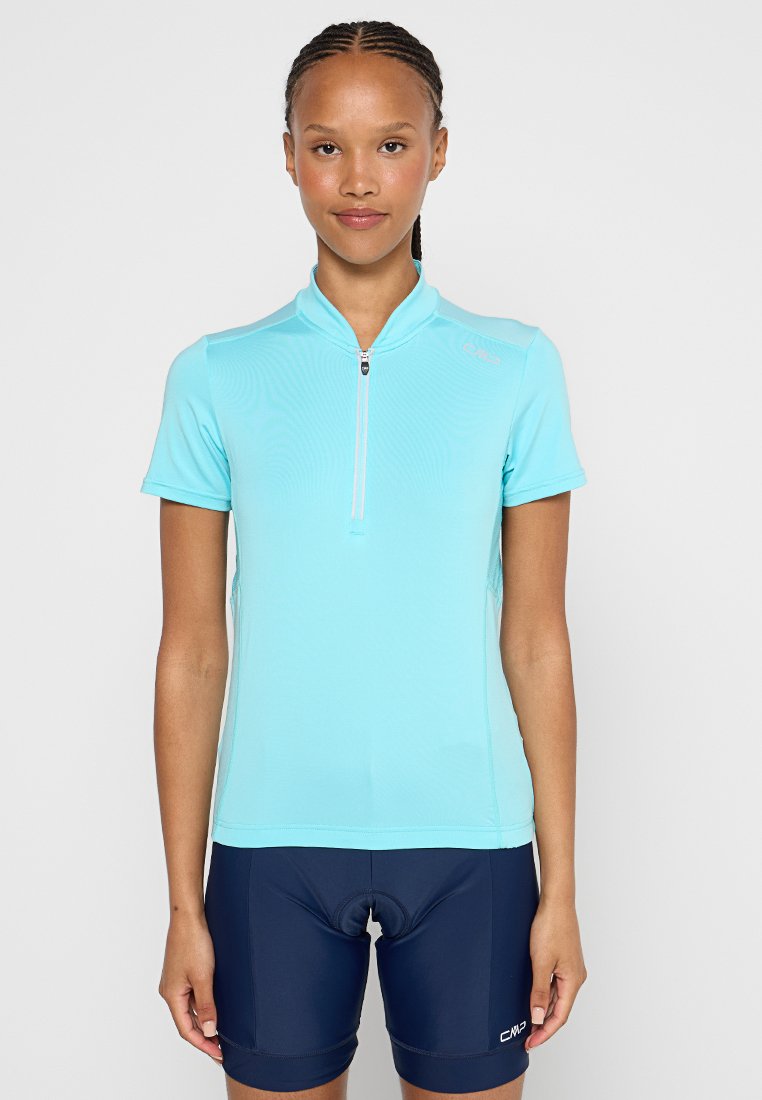 Himmelblaues Radtrikot mit kurzen Ärmeln und einem halben Reißverschluss. Das Material wirkt glatt und ist auf Komfort und Flexibilität ausgelegt. Dunkelblaue Shorts mit Polsterung.