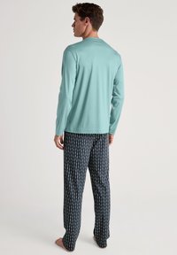 Lichtblauw overhemd met lange mouwen en marineblauwe pyjamabroek met een wit patroon, gemaakt van zachte stof, ontworpen voor comfort en ontspanning.