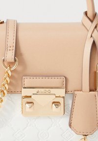 Borsa a mano in pelle beige con minuteria dorata, dotata di chiusura geometrica, tracolla a catena e base bianca testurizzata con un motivo sottile.