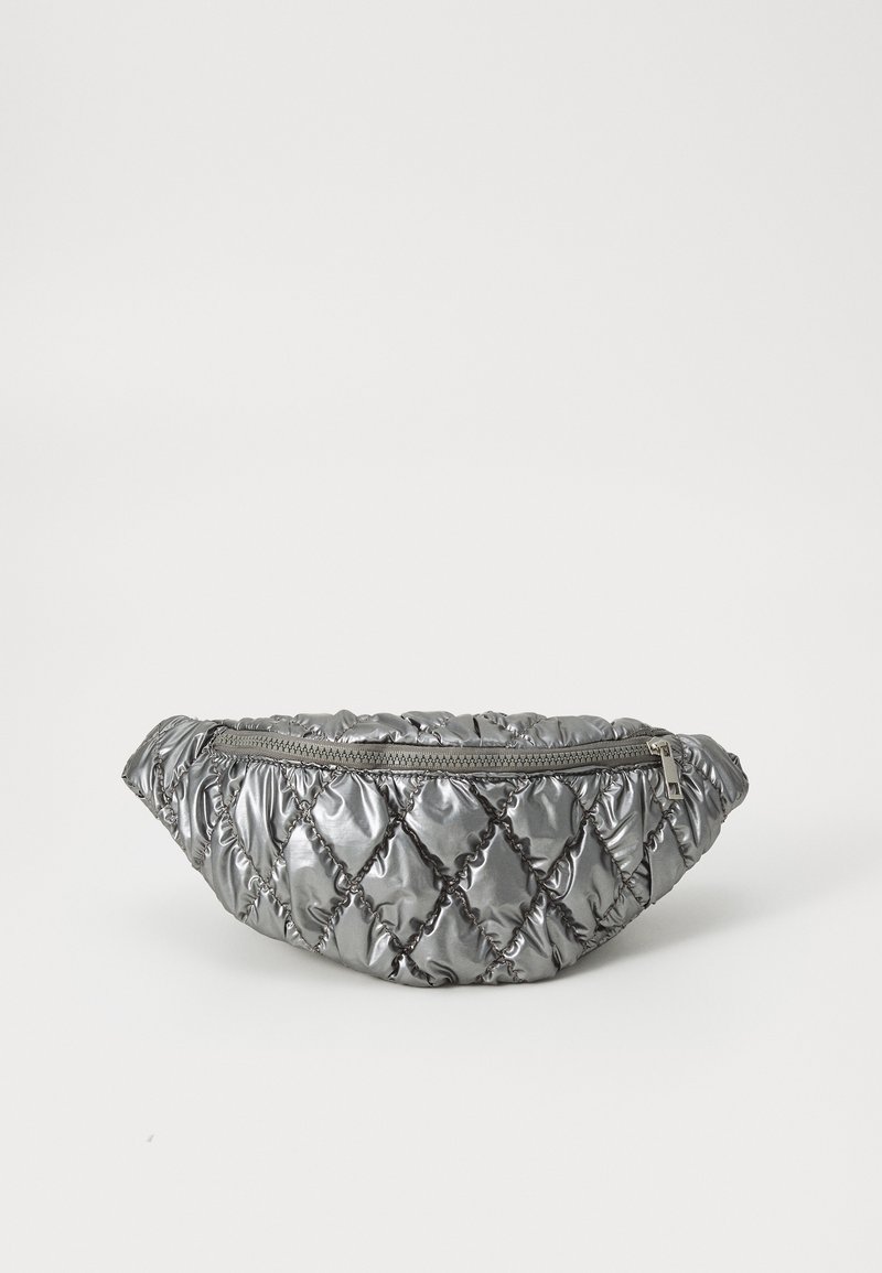 Borsa a vita metallizzata argento trapuntata con cuciture a diamante e chiusura con zip superiore su uno sfondo bianco.