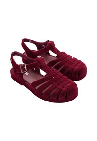 Sandalía de terciopelo rojo con diseño abierto, que presenta tiras horizontales y verticales, punta redondeada y una correa para el tobillo con una hebilla plateada.