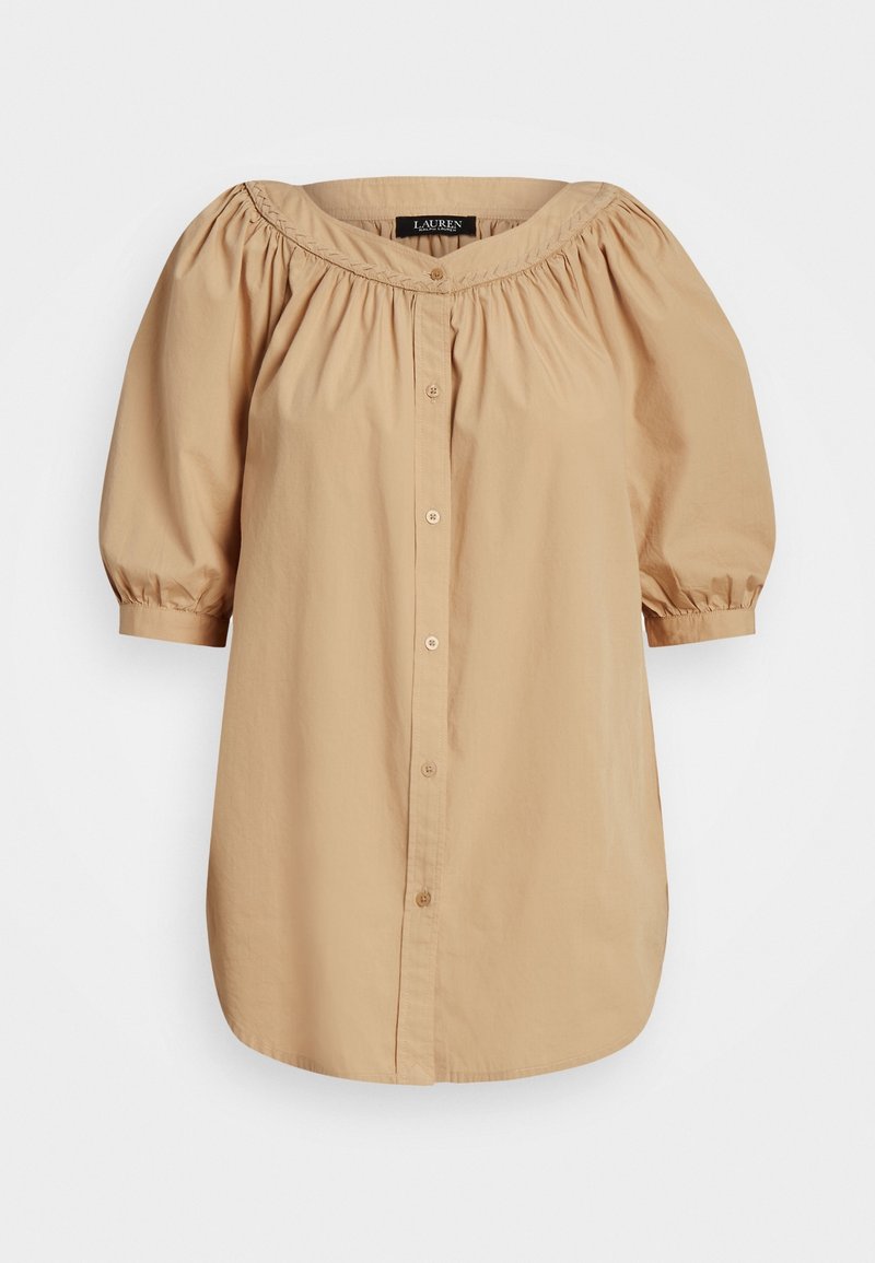 Blusa beige a spalle scoperte con maniche corte a palloncino, chiusura anteriore con bottoni e scollo arricciato. Realizzata in tessuto leggero con una texture liscia.