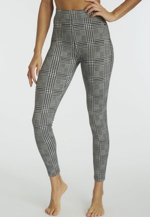Graue und schwarze gemusterte Leggings mit hoher Taille, die ein Karodessin und eine enganliegende Form aufweisen. Der Stoff wirkt glatt mit einem leichten Stretch.