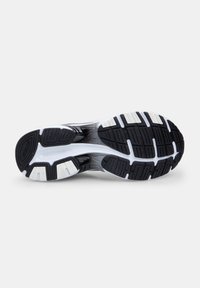 Black and white athletic shoe sole with rubber traction patterns, featuring a textured surface and reinforced sections for grip and stability.