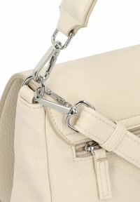 Bolso de mano de cuero crema con superficie texturizada, que cuenta con un clip de metal plateado y una correa ajustable con acentos de costura.