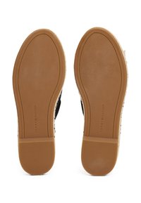 Paire de chaussures marron à semelles en caoutchouc vue du dessous, avec le texte ""Tommy Hilfiger"" embossé sur chaque semelle.